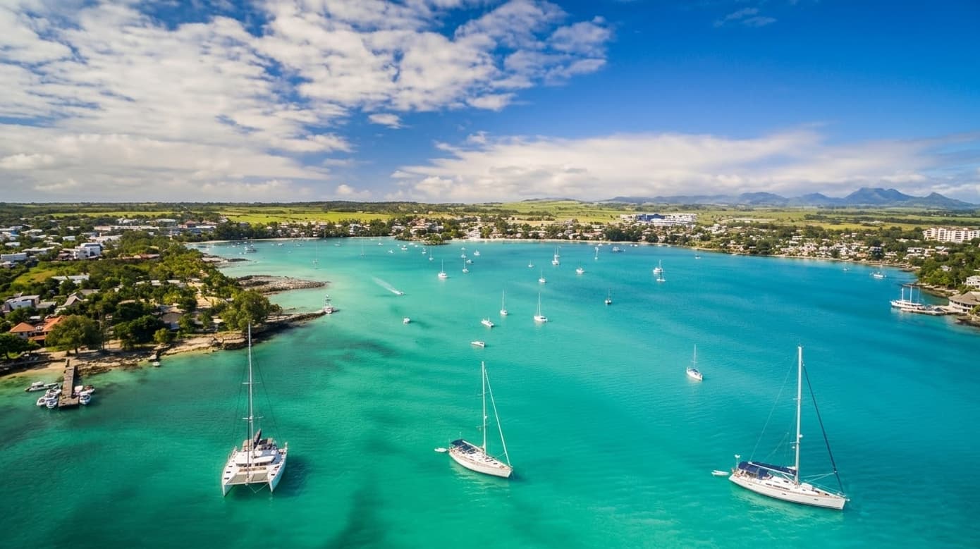 Aerial view of North Mauritius property coastline with turquoise lagoon, anchored boats, and coastal residential areas